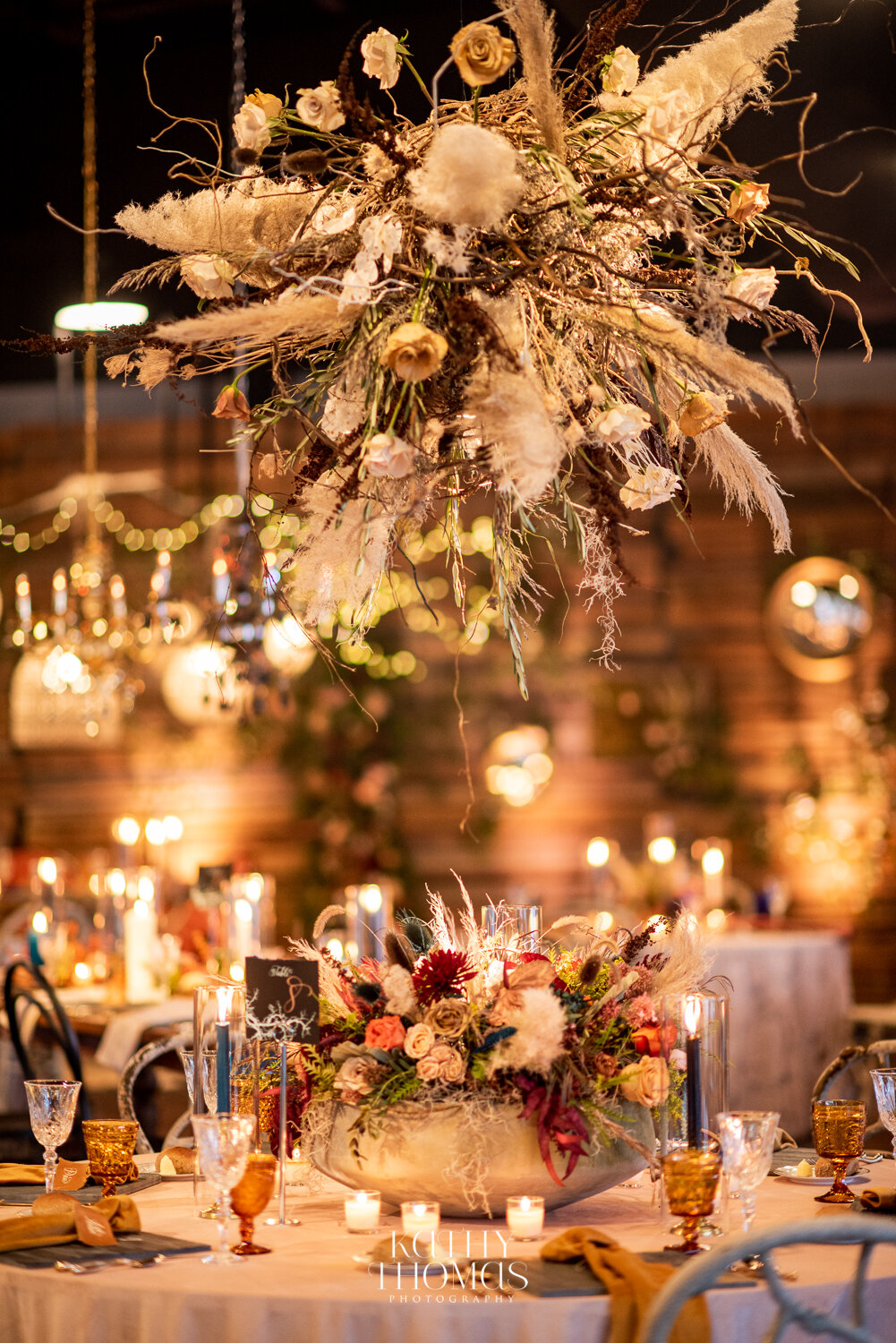 Dramatic suspended floral installation over a candlelit reception table
