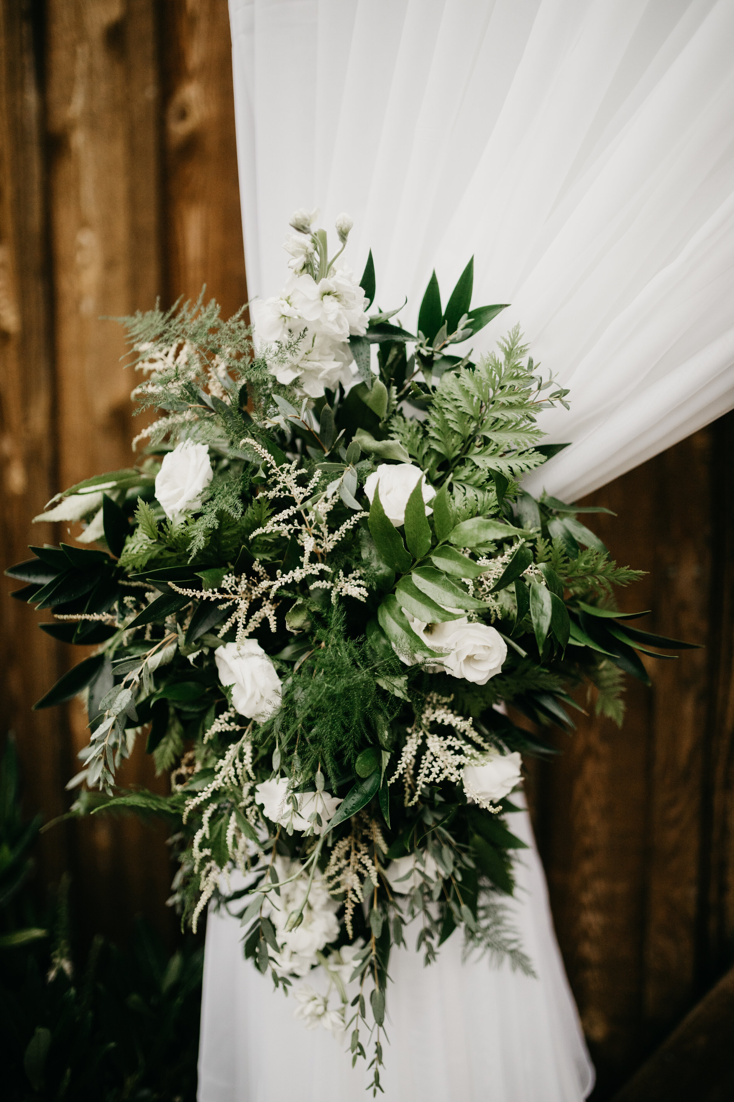 Greenery and white blooms on a soft ceremony drape